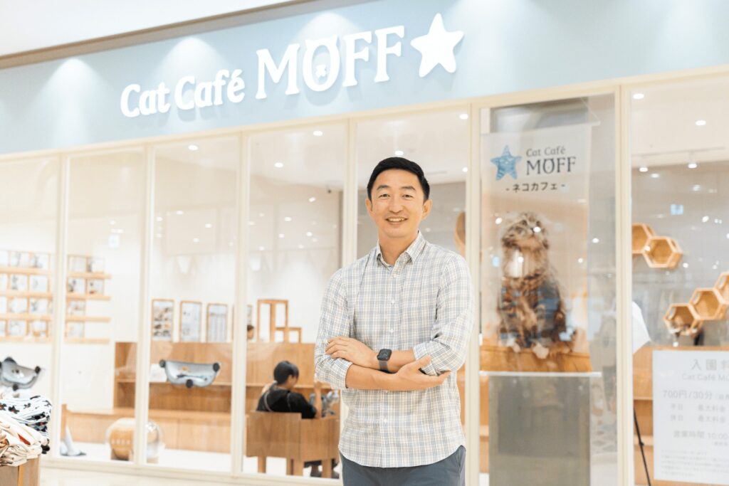 MOFF代表が店舗前で笑顔を見せる採用メッセージページ用写真